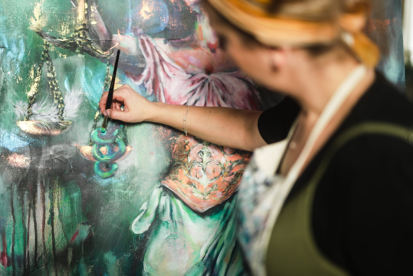 Katharina Hindes im Atelier, mit dem Pinsel an einem großformatigen Gemälde in Türkis und Gold.